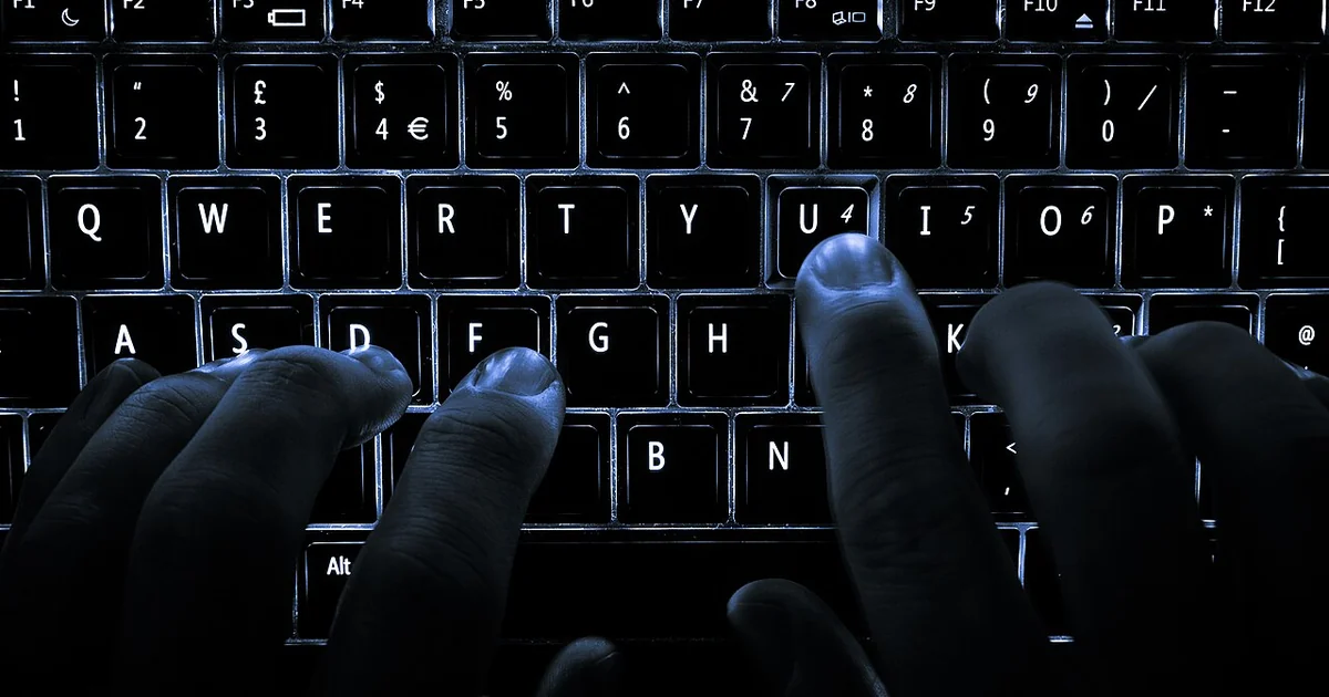 A backlit laptop computer keyboard. Most fingers are on the "home" keys for touch-typing; the 'U' key is being pressed.