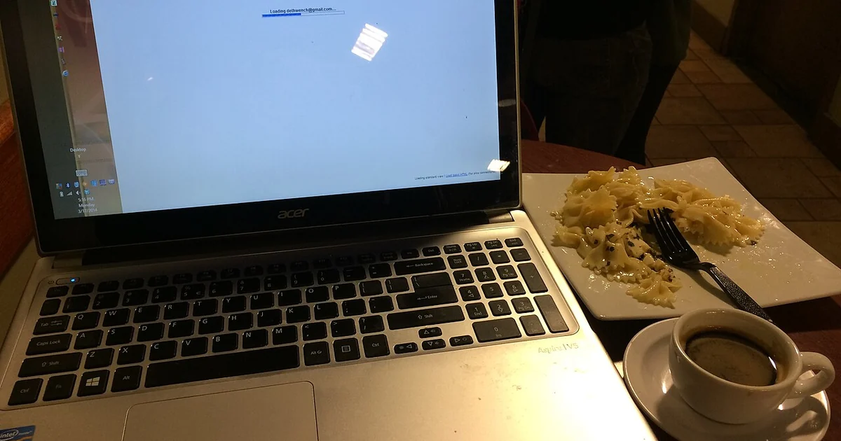 Laptop with food and drink at a cafe.